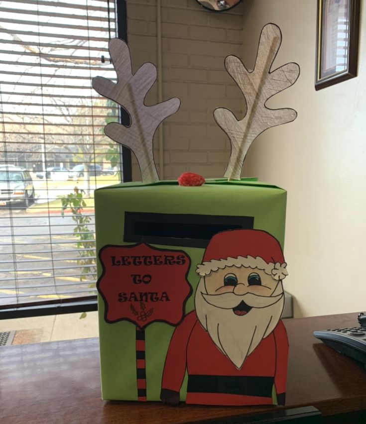 a green box with santa clause on it sitting on a table in front of a window