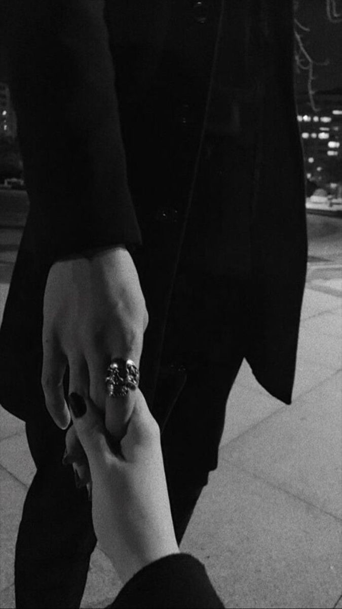 two people holding hands while walking down the street