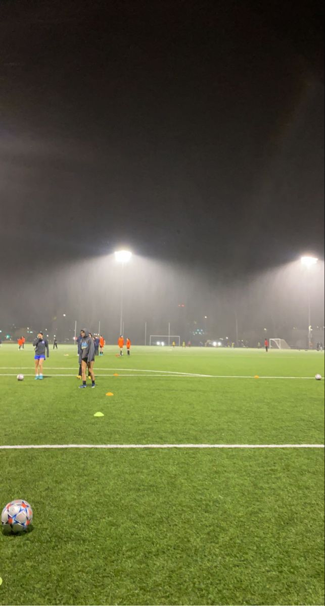 soccer players are practicing on the field at night