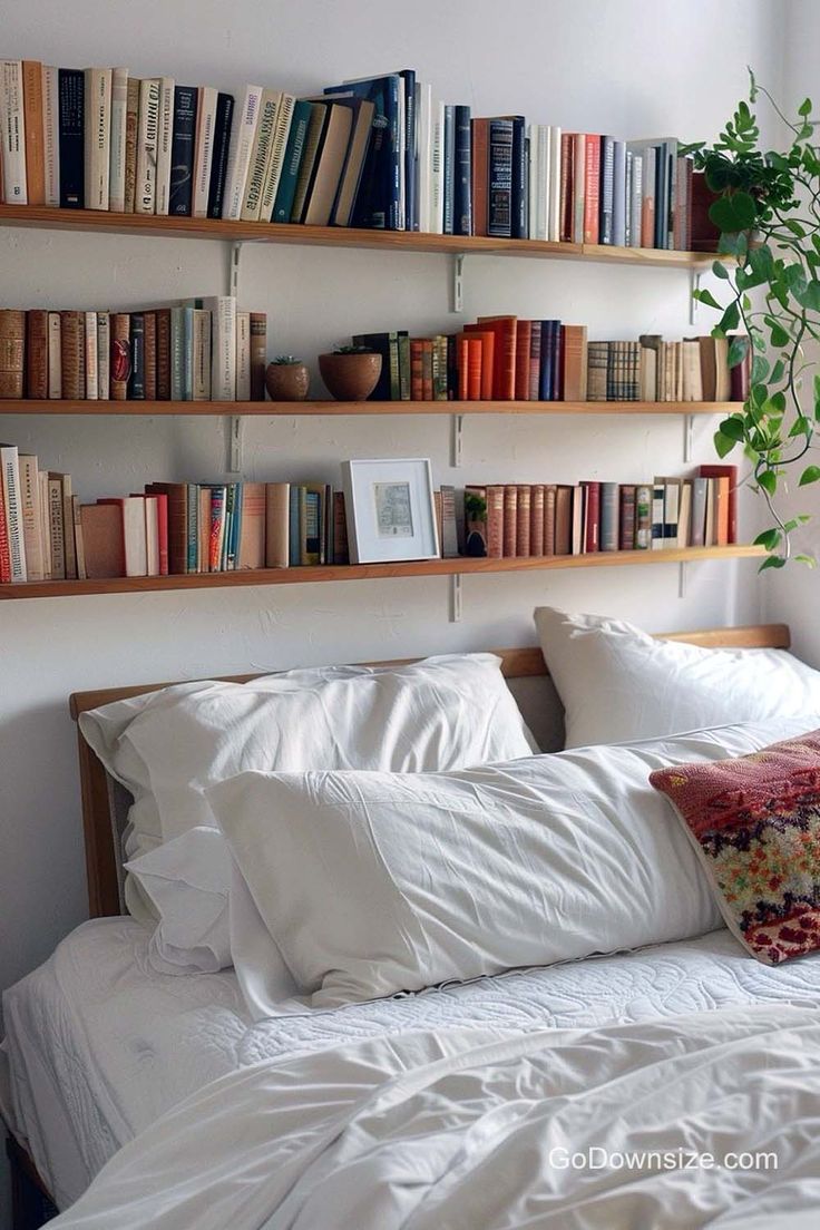 a bed topped with lots of books next to a wall filled with shelves full of books