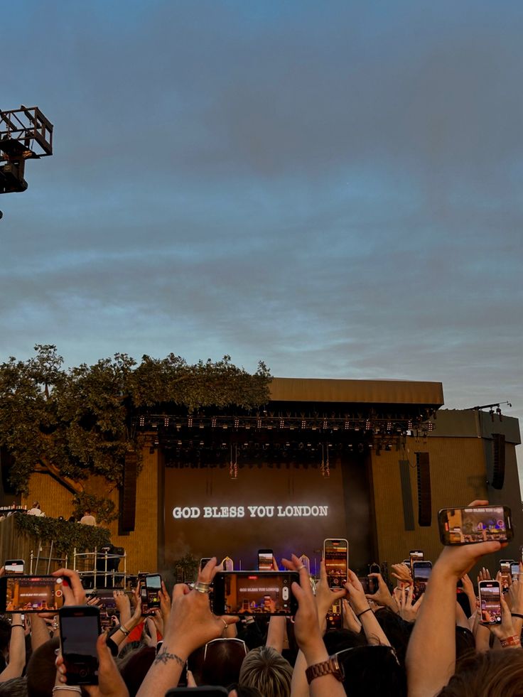 a crowd of people holding up their cell phones to take pictures at an outdoor concert