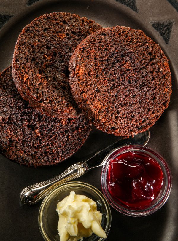 two brown breads with butter and jam on a plate next to a bowl of ketchup