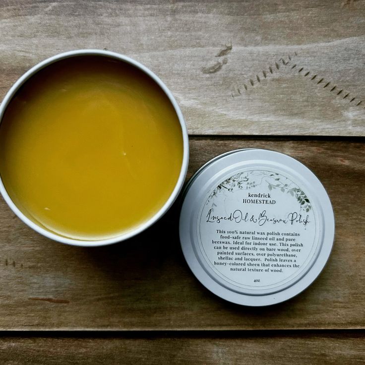 a white bowl filled with liquid next to a tin of lip bale on top of a wooden table