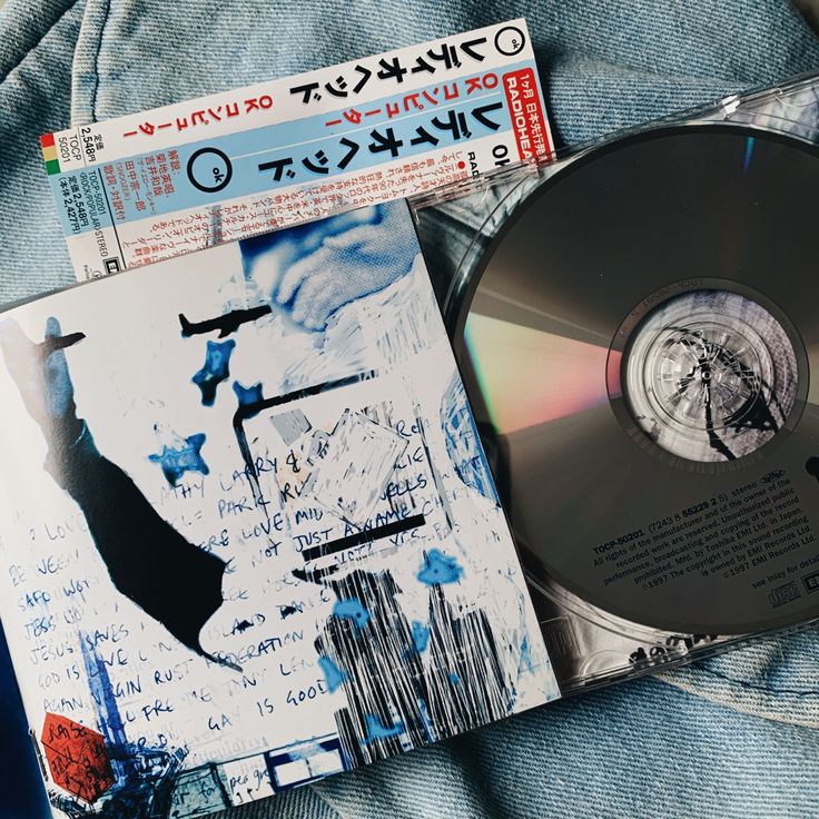 a cd sitting on top of a pair of blue jeans next to an album cover