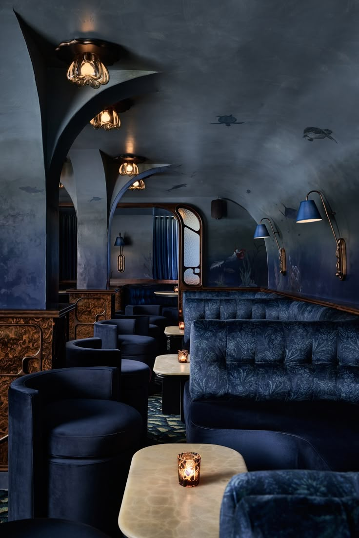 the interior of a restaurant with blue couches and gold table lamps on either side