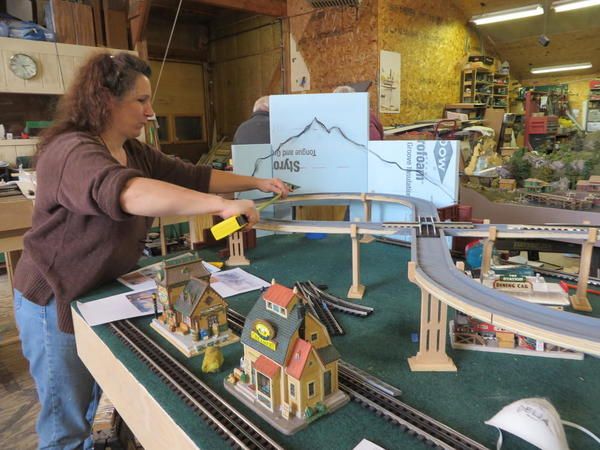 a woman standing in front of a model train set