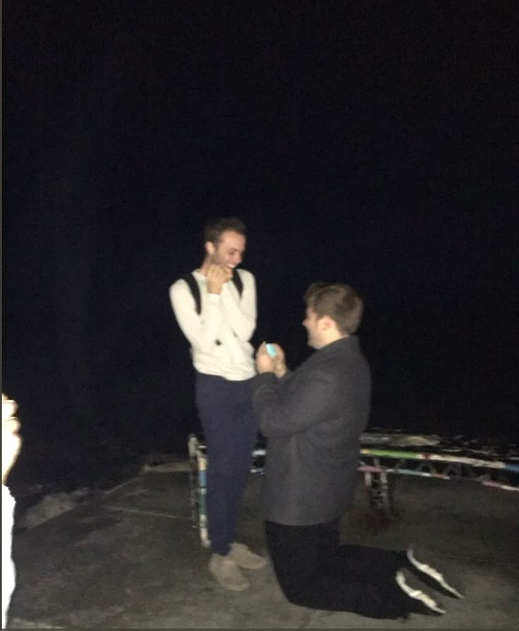 two men standing next to each other in the dark