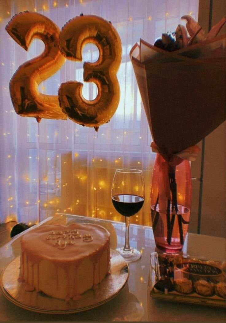 a table with a cake, wine glass and balloons in the shape of number 28