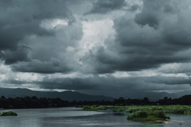 the sky is filled with dark clouds over a lake