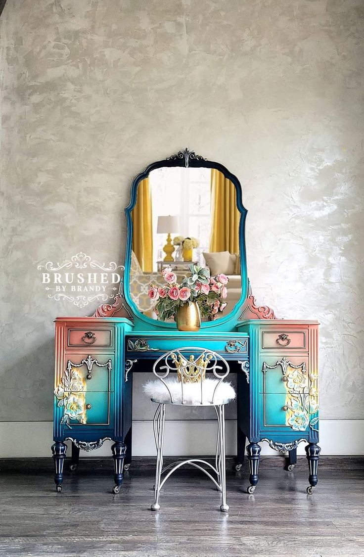 an ornate dresser and mirror with flowers on it in front of a wall mounted mirror