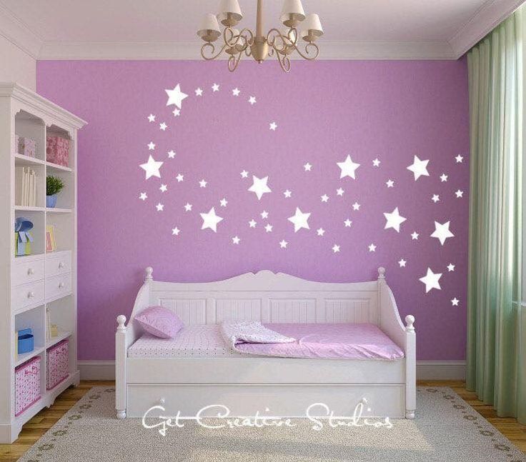 a bedroom with purple walls and white stars on the wall