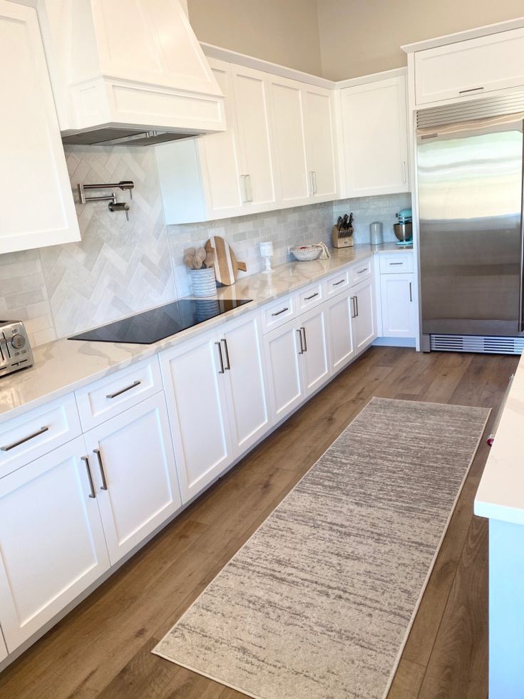 a kitchen with white cabinets and stainless steel refrigerator freezer next to an island counter