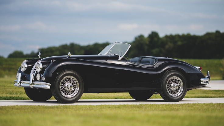 an old black sports car is parked on the road