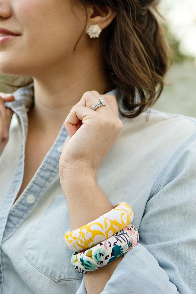 a woman with two bracelets on her wrist wearing a blue shirt and denim shirt