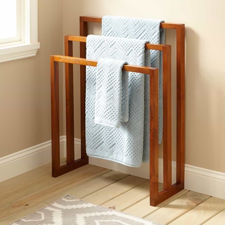 a towel rack with two towels on it in a bathroom next to a rug and window