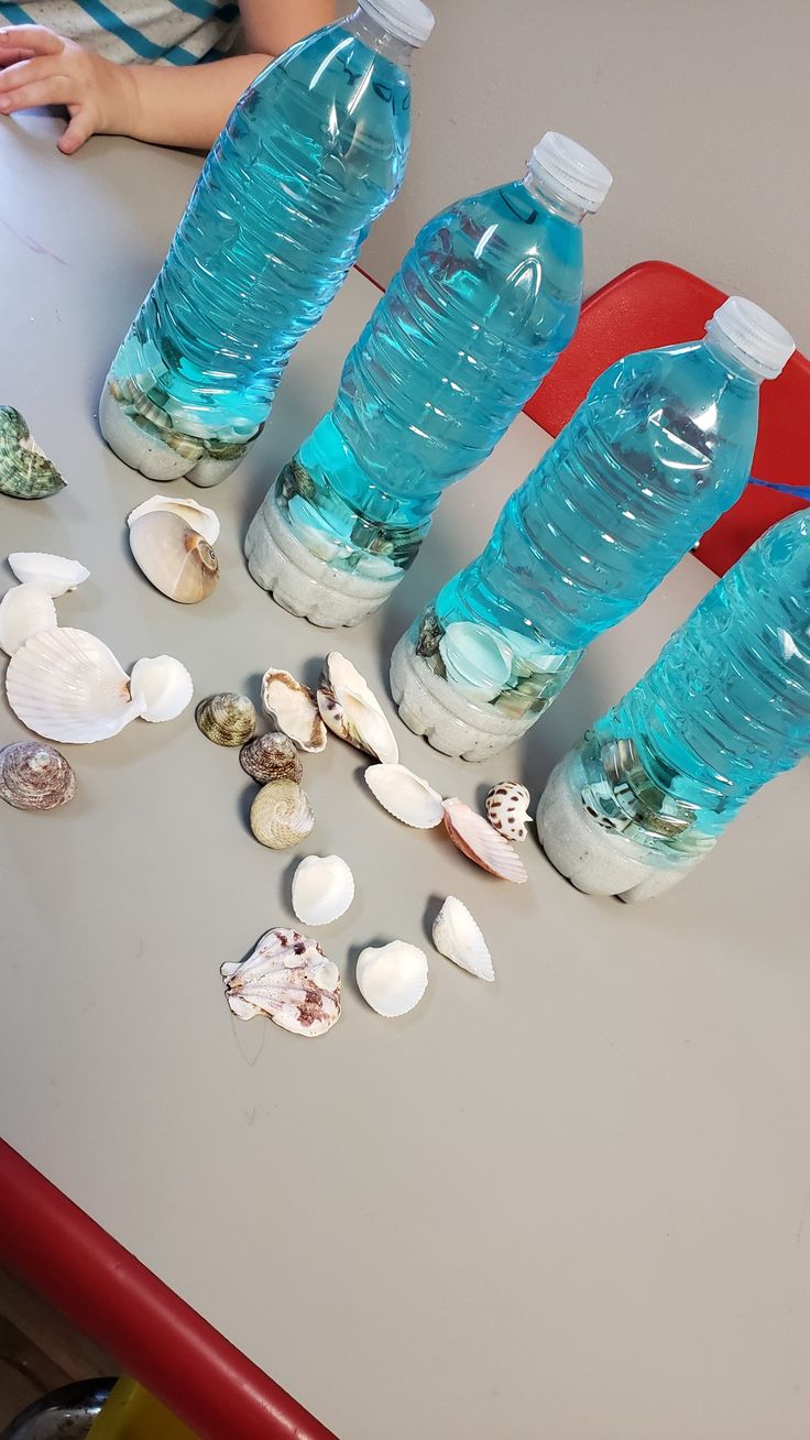 several bottles of water sitting on top of a table next to seashells and shells