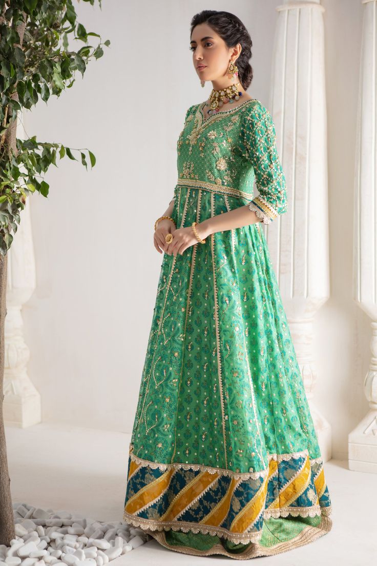 Make a colorful style statement with our beautifully crafted ensemble, gorgeous hand block printed kalidar, heavily embellished with sequins, beads and gota boti chan, neckline and sleeves are beautifully adorned with gorgeous zardozi work, stunning teal & Dhani green hued chata pati appliquéd border on hem finishes it beautifully, gorgeous detailed back and hand-made tassels gives entire outfit a trendy element. This stunning kalidar is offset with jamawar Lehanga and gorgeous Maysuri dupatta featuring gota motifs and heavily embellished chan, trimmed with gota borders , a Must- have wardrobe staple to carry all Wedding Festivities in effortless style. Kalidar Fabric: Pure Silk Net Lehanga Fabric: Jamawar Dupatta Fabric: Pure Maysuri Outfit Color: Opal This outfit is only available in Cus Reception Anarkali Set With Dabka Work For Navratri, Anarkali Choli In Chanderi With Dabka Details, Navratri Salwar Kameez With Chandbali Mirror Work, Eid Anarkali Set With Gota Work And Kundan Material, Eid Anarkali Set With Gota Work And Kundan, Chanderi Choli For Reception With Straight Kurta, Bollywood Style Kurta With Cutdana For Reception, Designer Green Choli With Dabka Detailing, Traditional Floor-length Kundan Kurta