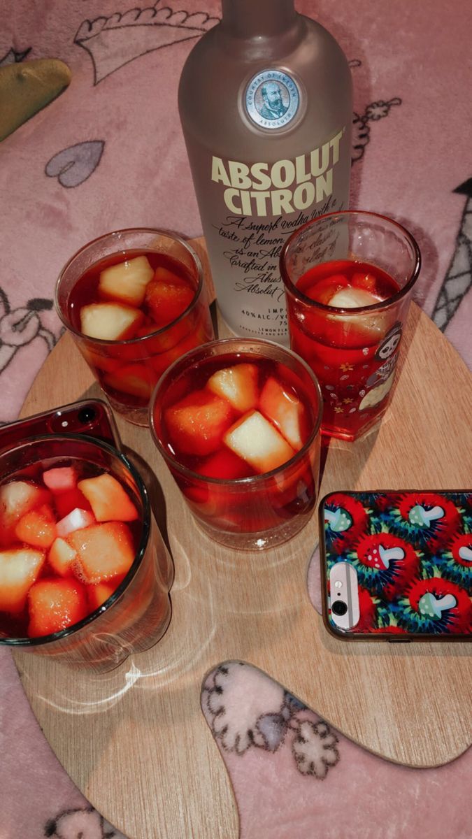 four glasses filled with liquid sitting on top of a wooden tray next to a bottle