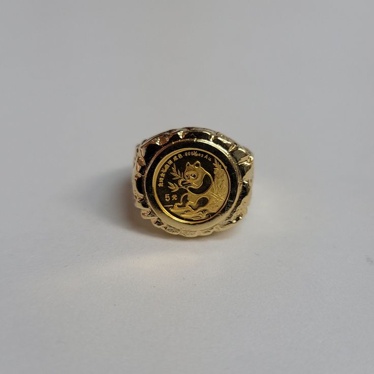 a gold ring with an image of a lion on the front and side, sitting on a white surface