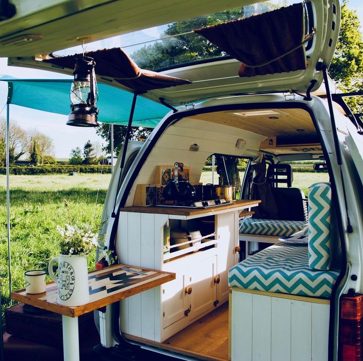 the interior of a camper van with its door open and table in the back