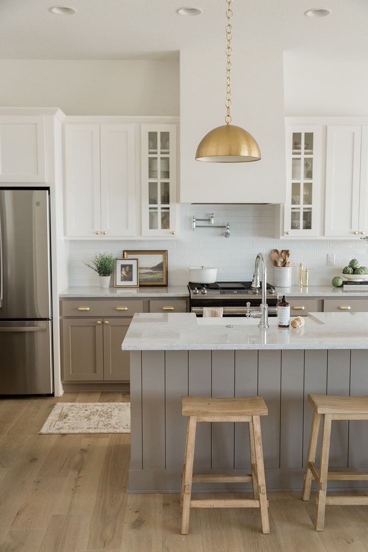 a kitchen with two stools in front of an island and stainless steel refrigerator freezer