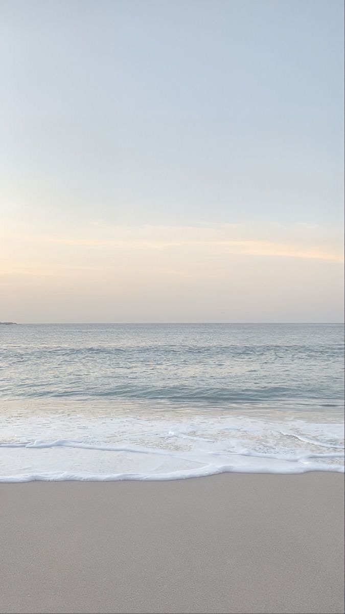 an empty beach with the ocean in the background