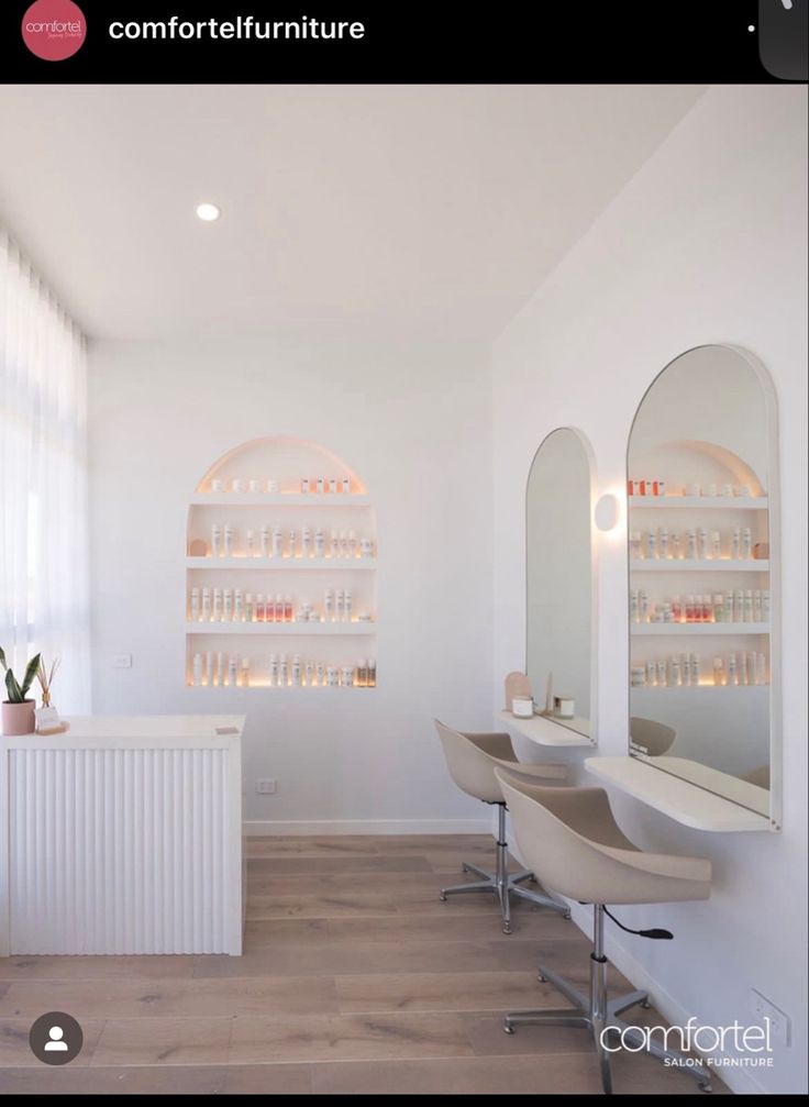 the interior of a hair salon with chairs, mirrors and shelves filled with bottles on white walls