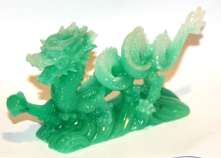 a green dragon figurine sitting on top of a white surface