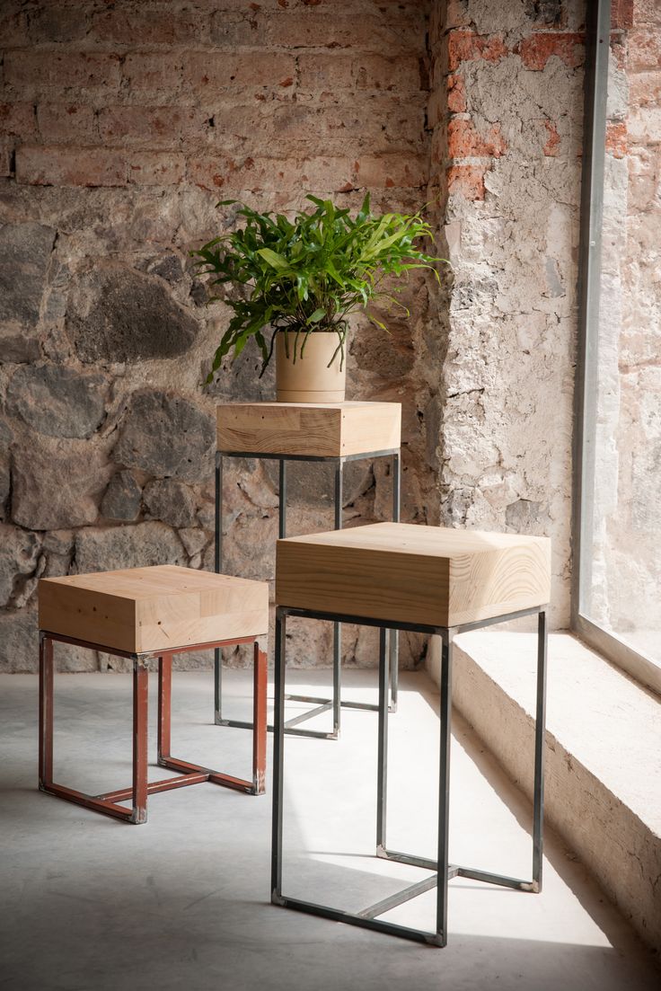 three tables with plants on them in front of a stone wall and window sill