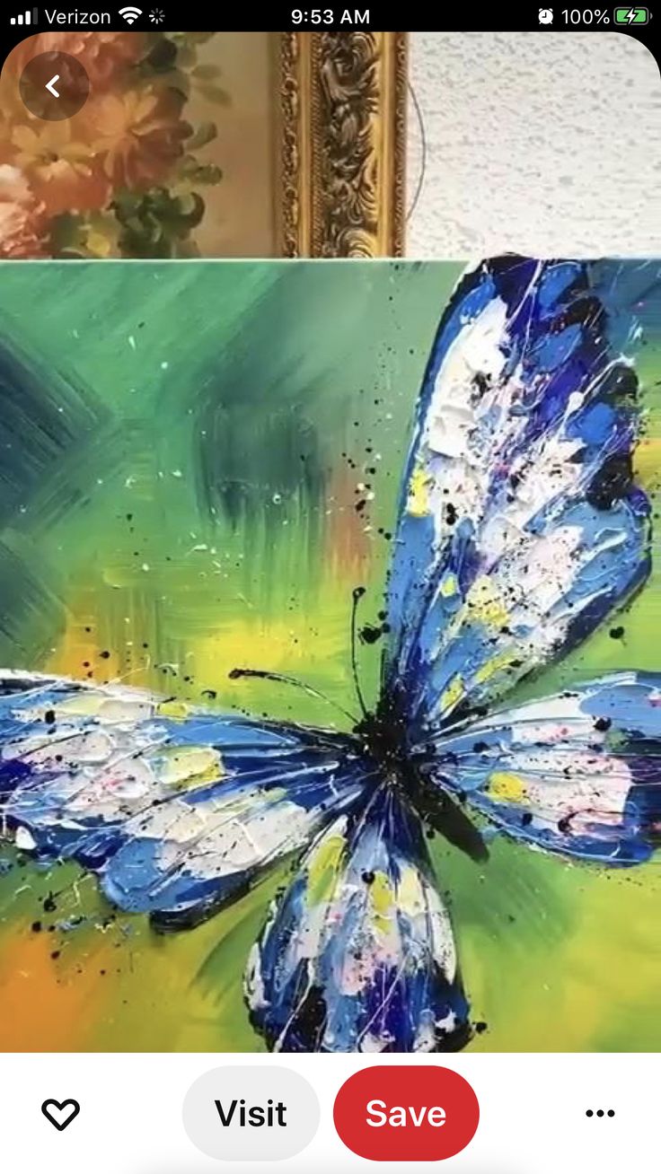 a blue butterfly painted on an easel in front of a painting