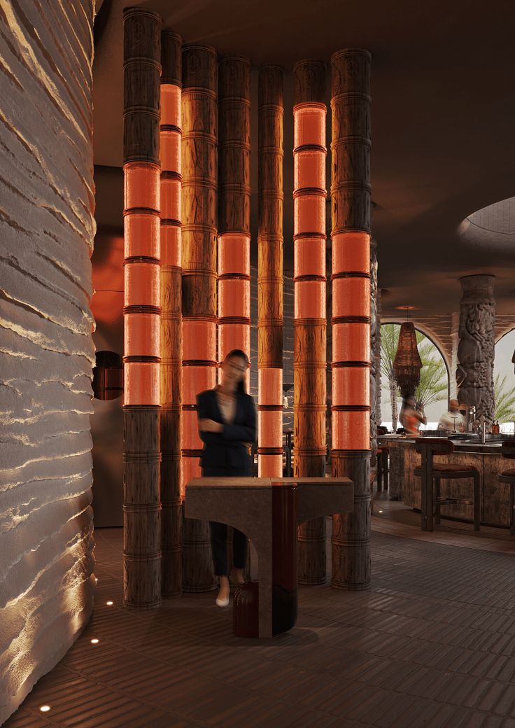 a person sitting on a bench in front of some tall bamboo columns with orange lights