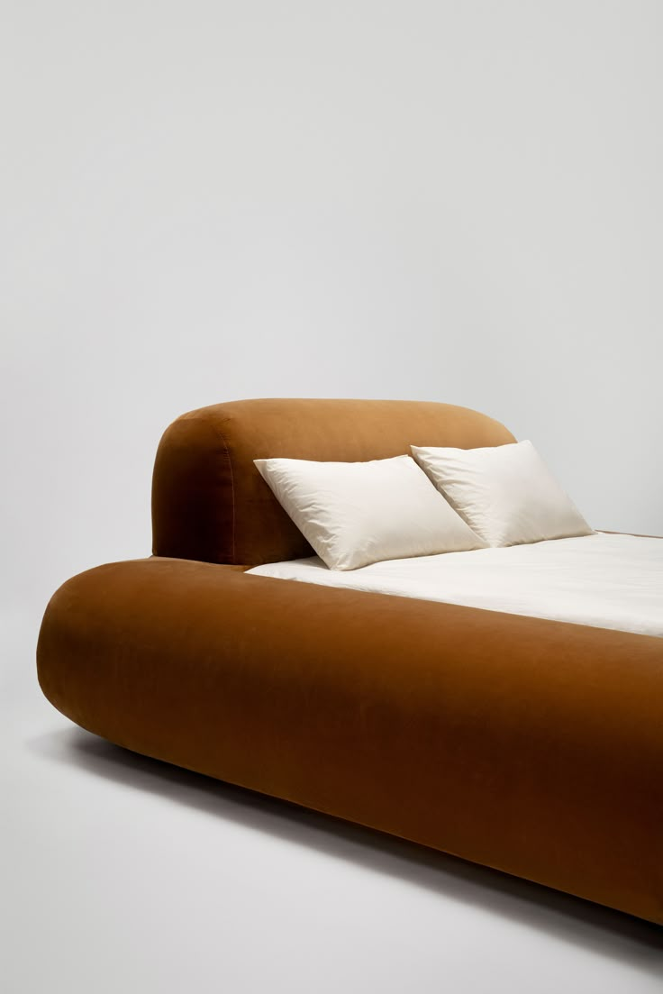 a bed with two pillows on top of it and a white wall in the background