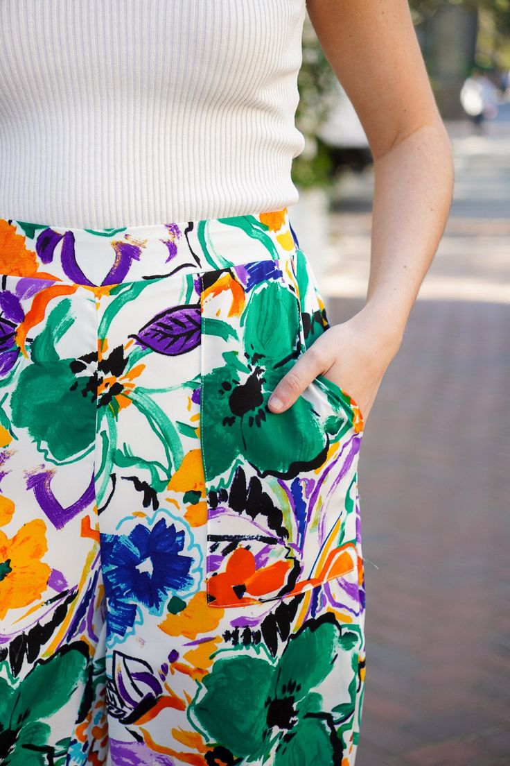 Get ready to light up the room with our Aurora Lights Pants! These high-waisted straight leg pants feature a vibrant and playful multi floral print in green, blue, purple, orange, and black hues. They feature an elastic waist at the back and square pockets that add comfort and functionality, making them the perfect addition to your spring and summer wardrobe. Pair with our Bristol Collared Tank to complete the look. They are lightweight, non-sheer, and fit true to size. 100% Polyester Brand- Ent Summer Multicolor Floral Wide Leg Pants, Spring Vibrant Print Wide-leg Pants, Vibrant Print Wide Leg Summer Bottoms, Spring Wide-leg Pants With Vibrant Print, Wide Leg Bottoms With Vibrant Print For Summer, Trendy Vibrant Print Summer Pants, Casual Multicolor Floral Print Pants, Trendy Summer Pants With Vibrant Print, Casual Wide Leg Bottoms With Vibrant Print