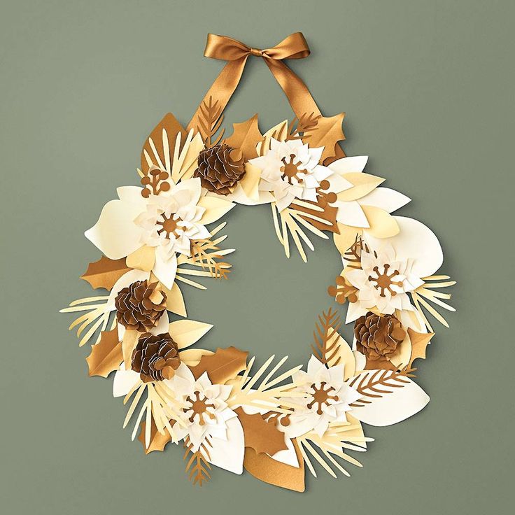 a christmas wreath made out of paper and gold ribbon on a green background with pine cones