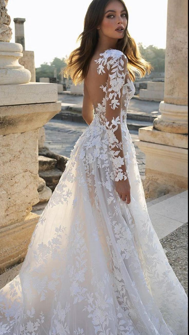 a woman in a white wedding dress standing on the ground with her back to the camera