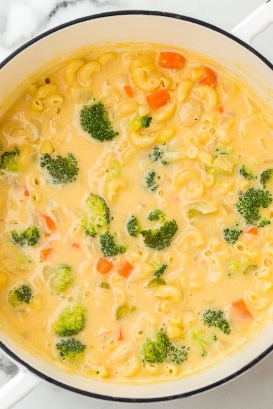 broccoli, carrots, and noodles are in a pot on the stove