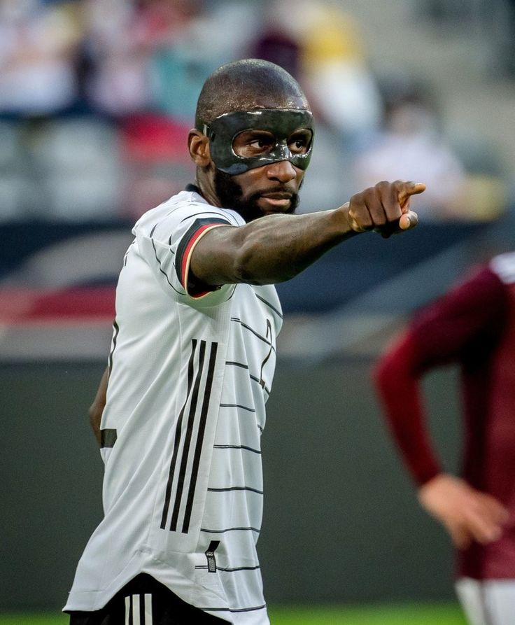 a soccer player points at the ball during a game with other players in the background