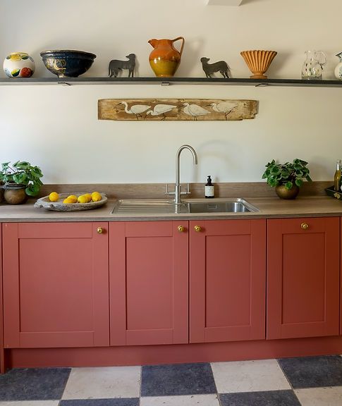 a kitchen with red cabinets and black and white checkerboard flooring on the walls