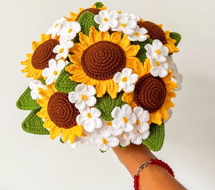 a hand holding a crocheted sunflower bouquet