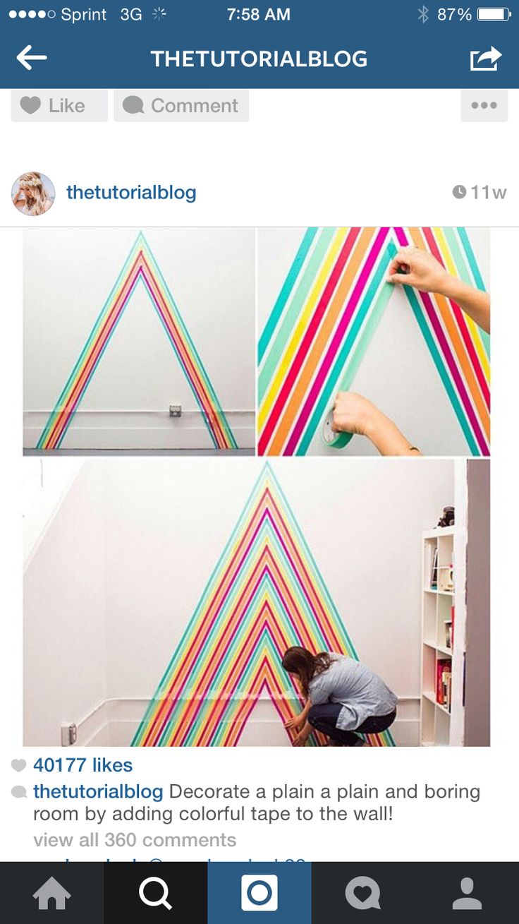 the man is painting on the wall with multicolored stripes and he is doing something