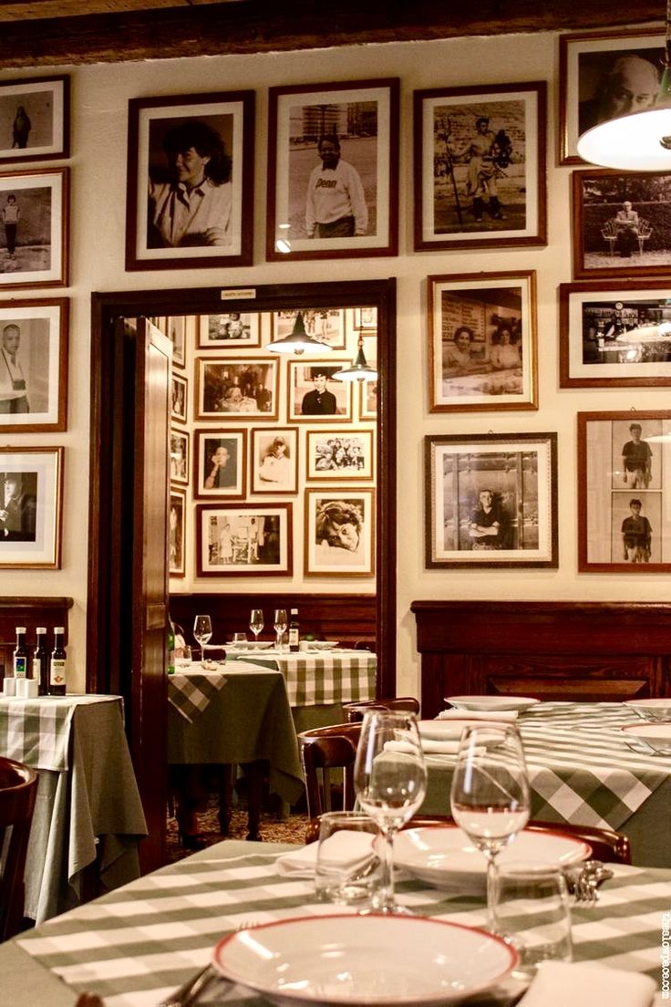 a dining room with pictures on the wall and table cloths set for two people