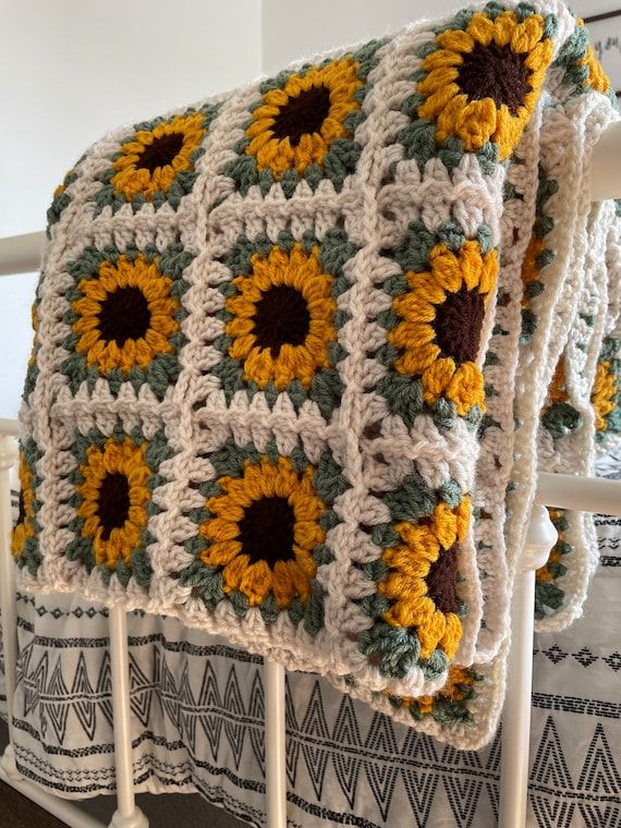 a crocheted blanket with sunflowers on it is sitting on a bed