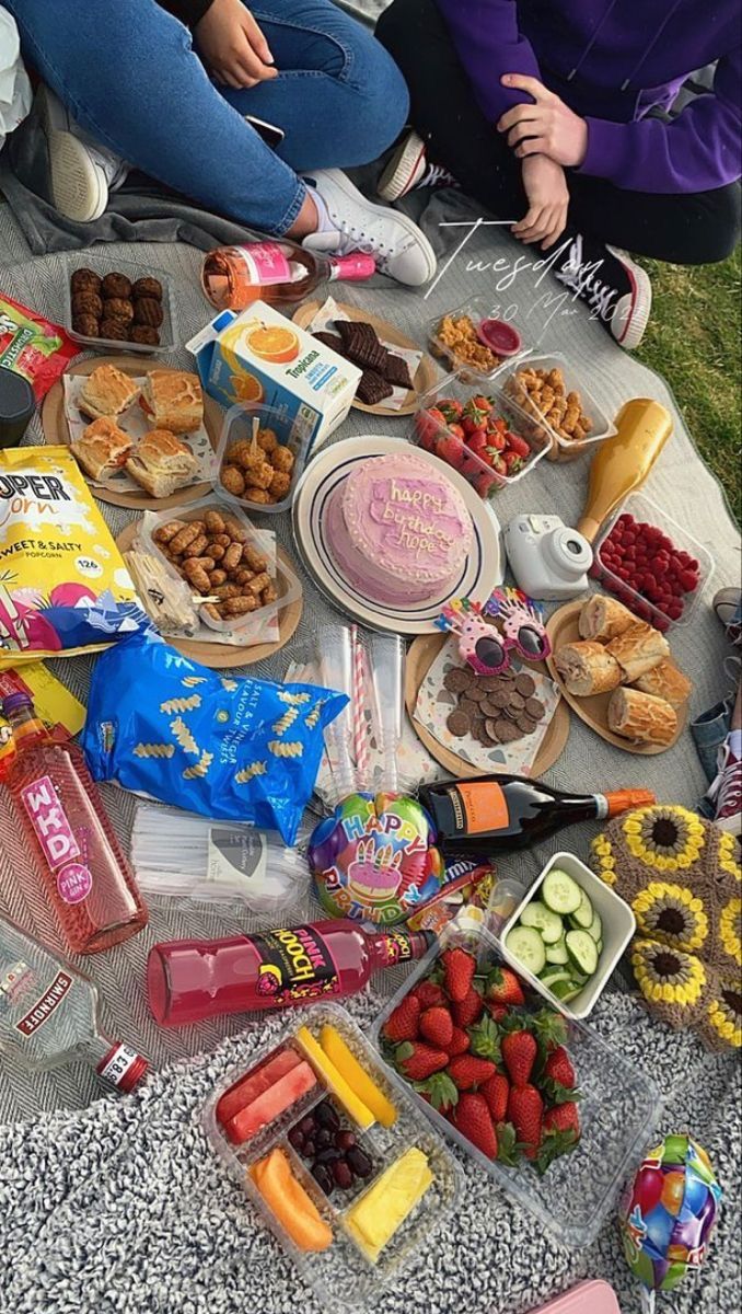 two women sitting on the ground with food and snacks