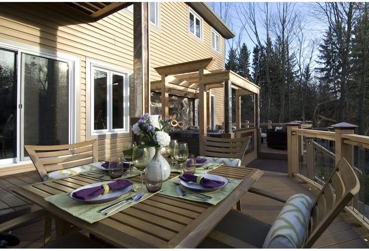 an outdoor dining area with table and chairs on the deck overlooking the trees in the back yard