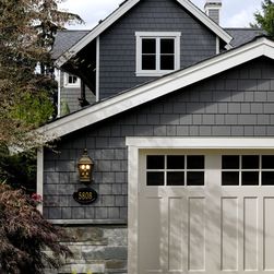 a gray house with two white garage doors and three different color swatches on it