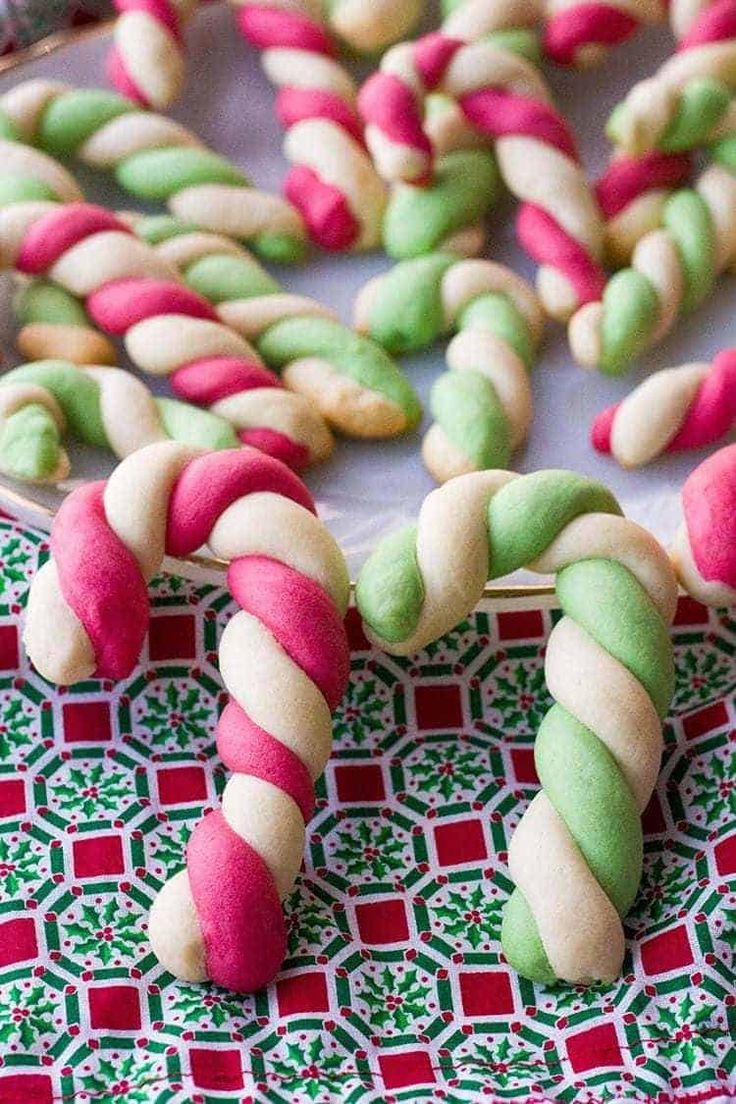 some candy canes and cookies are on a table with red and green napkins