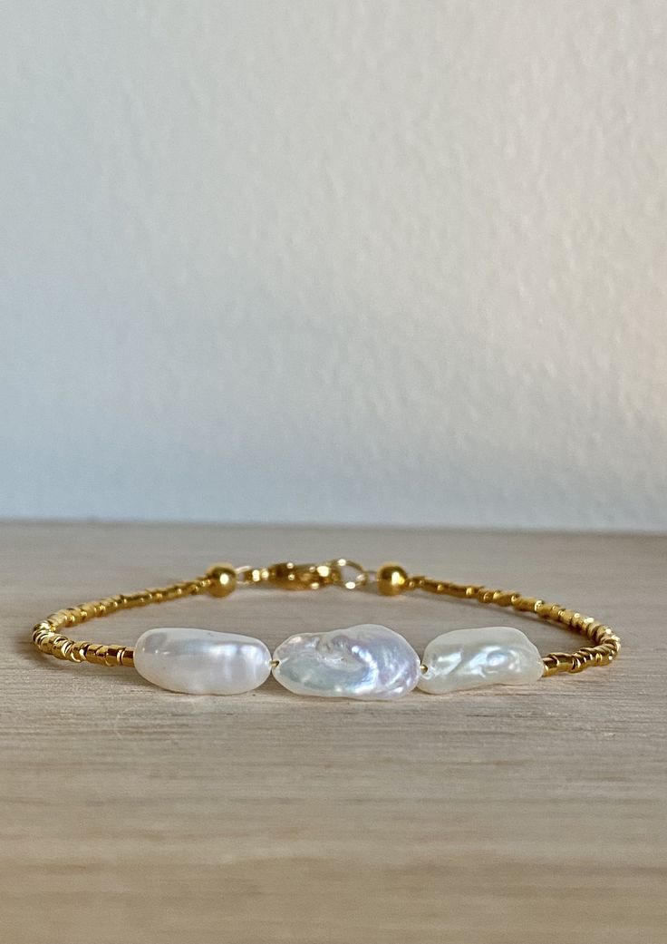 This bracelet is hand strung with 1.6mm duracoat galvanized 24K yellow gold-plated beads, 3 long freshwater pearls, and finished off with a gold-plated jump ring and lobster-claw clasp. The natural elements of each pearl are unique and sure to make your bracelet one of a kind. Note: The photos associated with this listing are an example of what your bracelet will look like; yours will not be this exact one. Great for stacking! Sizing: Extra Small Average Women's Wrist Sizes: 5.5in Average Women' Handmade Gold Bracelet With Round Beads, Handmade Gold-plated Beaded Bracelets, Adjustable Gold Single Strand Beaded Bracelet, Single Strand Baroque Pearl Bracelet As Gift, Adjustable Gold Pearl Drop Bracelet, Handmade Adjustable Yellow Gold Pearl Bracelet, Adjustable Yellow Gold Pearl Bracelet With Gold Beads, Gold Pearl Single Strand Beaded Bracelets, Adjustable Handmade Yellow Gold Pearl Bracelet