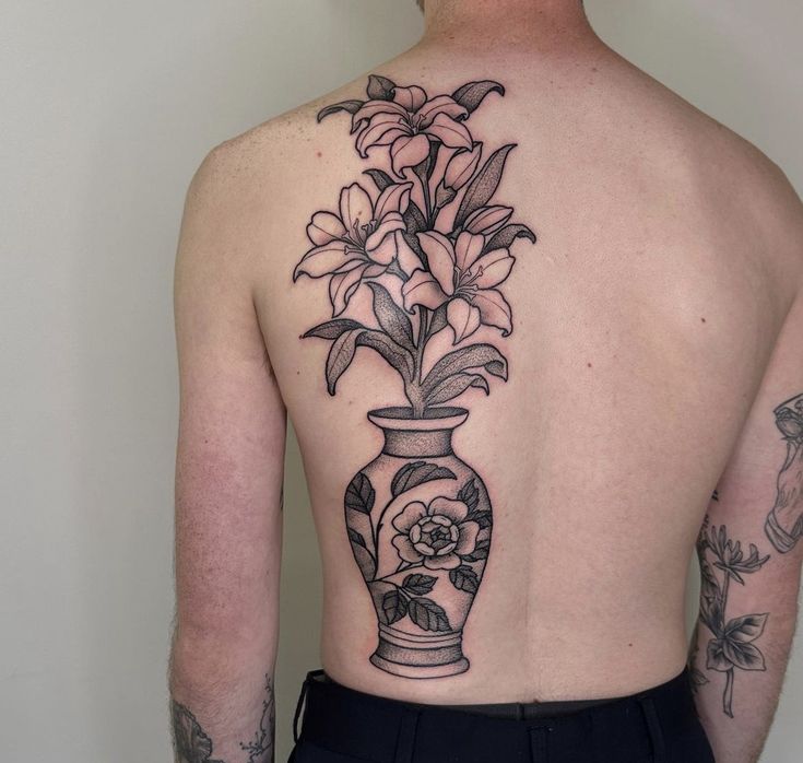 the back of a man's upper body with flowers in a vase on it