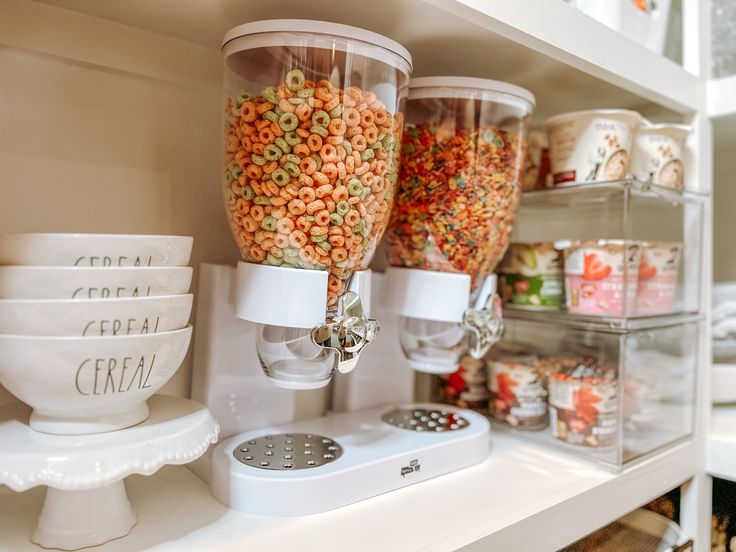 there are many cups and bowls on the shelves in this kitchen that is stocked with cereal