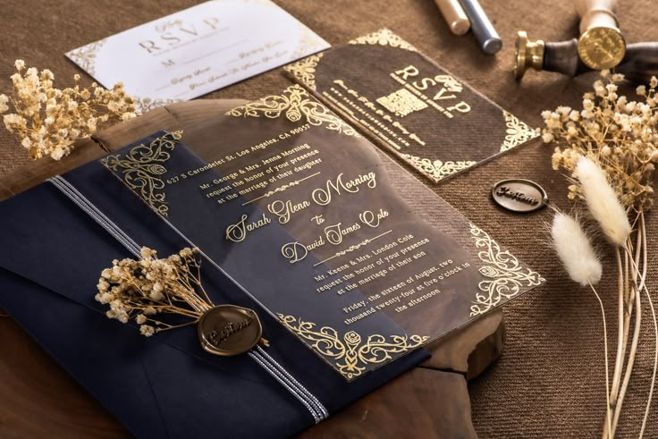 the wedding stationery is laid out on top of an old book and some feathers